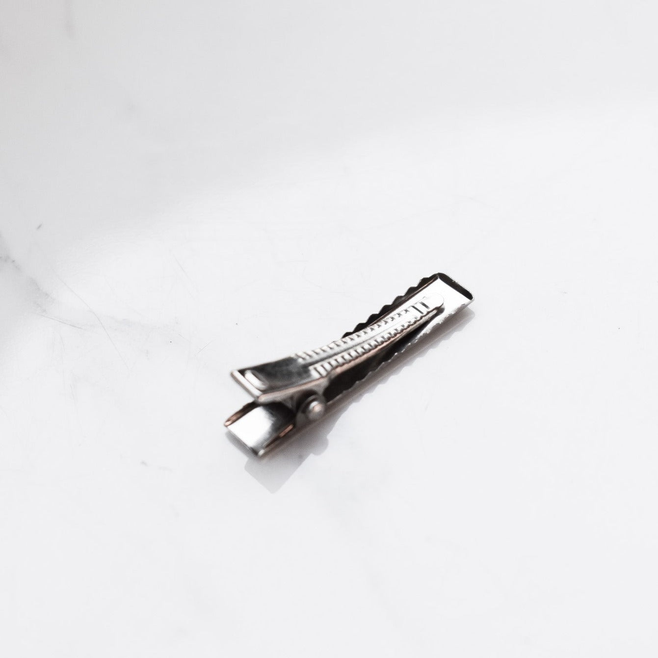 Silver coloured rectangle alligator hair clips.